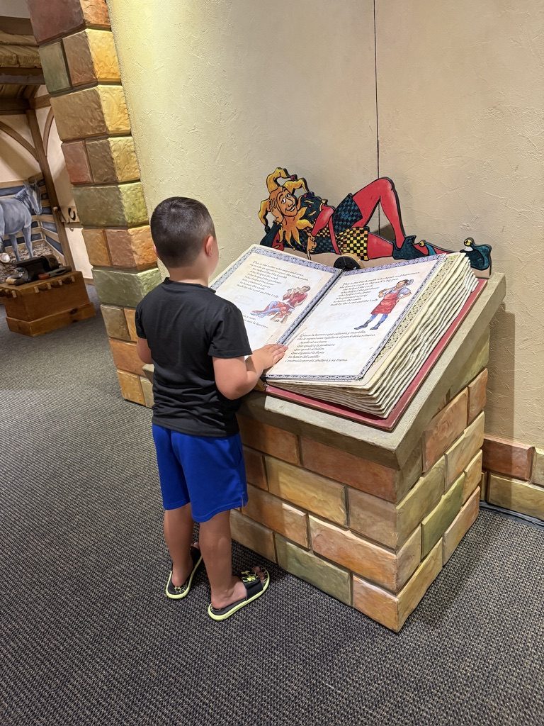 A boy reading a giant storybook on a stone pedestal