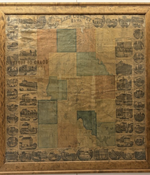 An antique framed wall map of Linn County, Iowa, hanging on a wall
