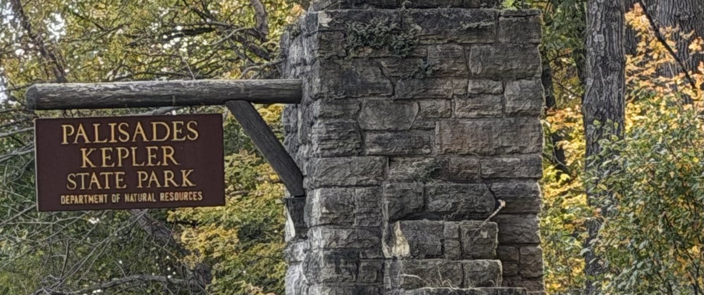 The stone gate pillar and brown Palisades-Kepler State Park sign surrounded by fall leaves